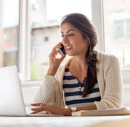 Woman using a cellphone and a laptop.